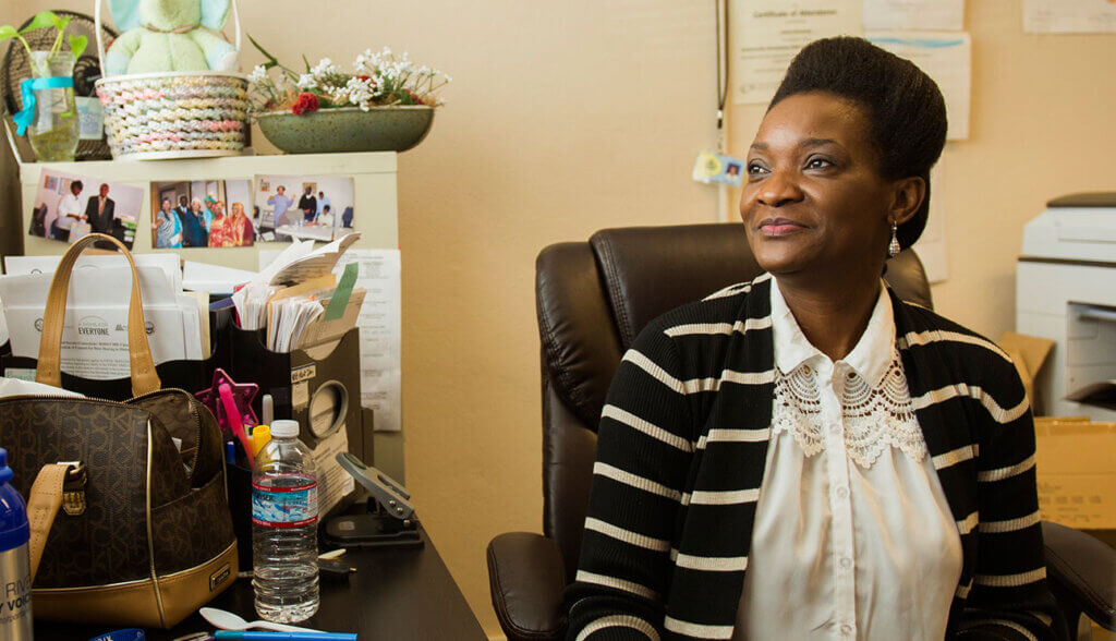 Woman sitting at her desk in an office smiling and looking away from the camera
